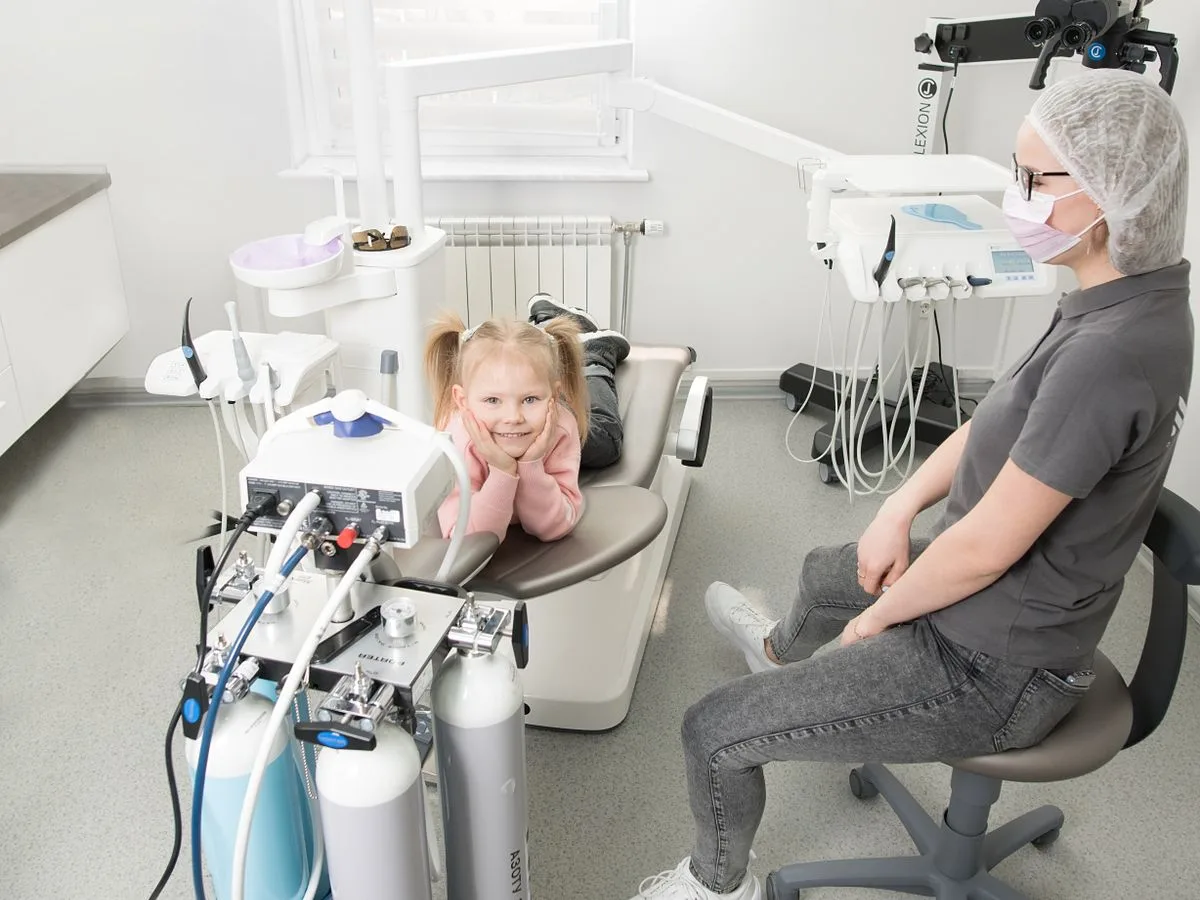 Odontóloga atendiendo a una niña acompañada de su madre en la clínica dental